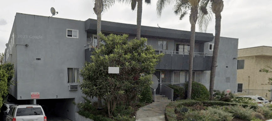 A grey building with a tree in front of it.